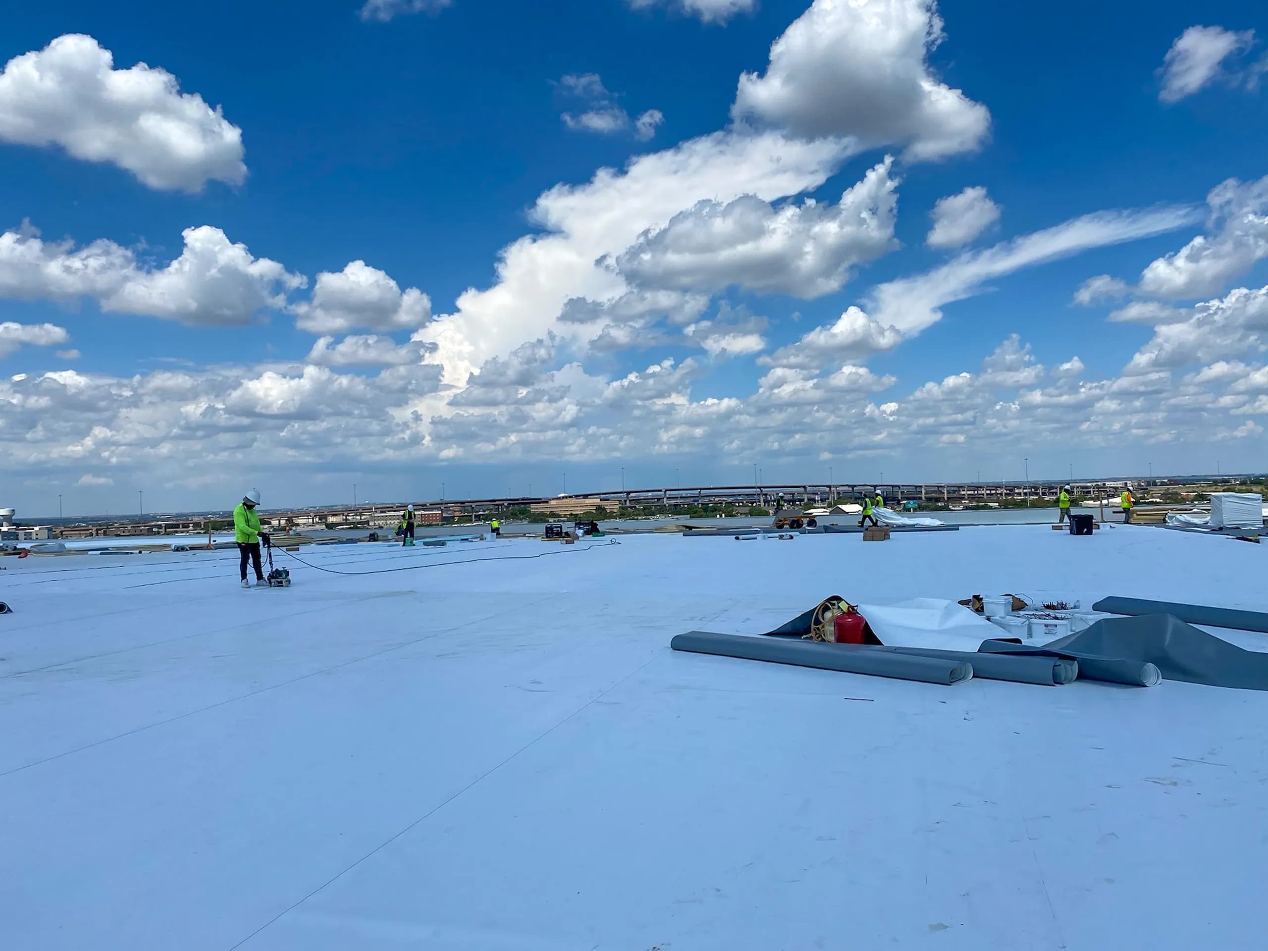 Commercial roofing crew installing TPO on a large flat roof