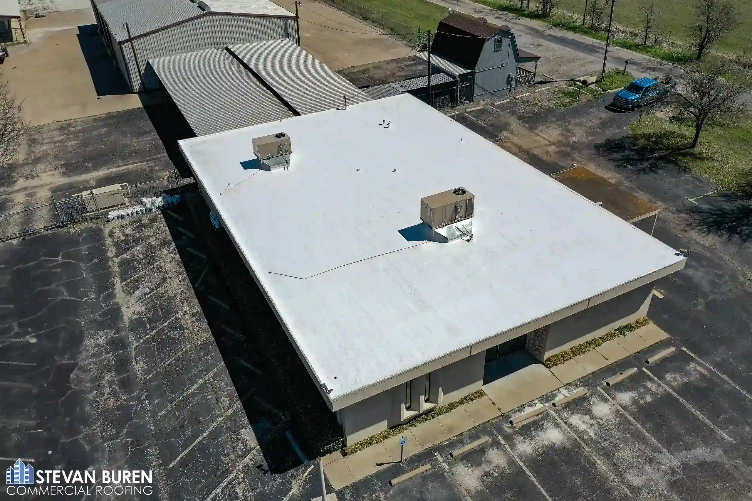 Aerial view of a commercial facility with a white roof coating system