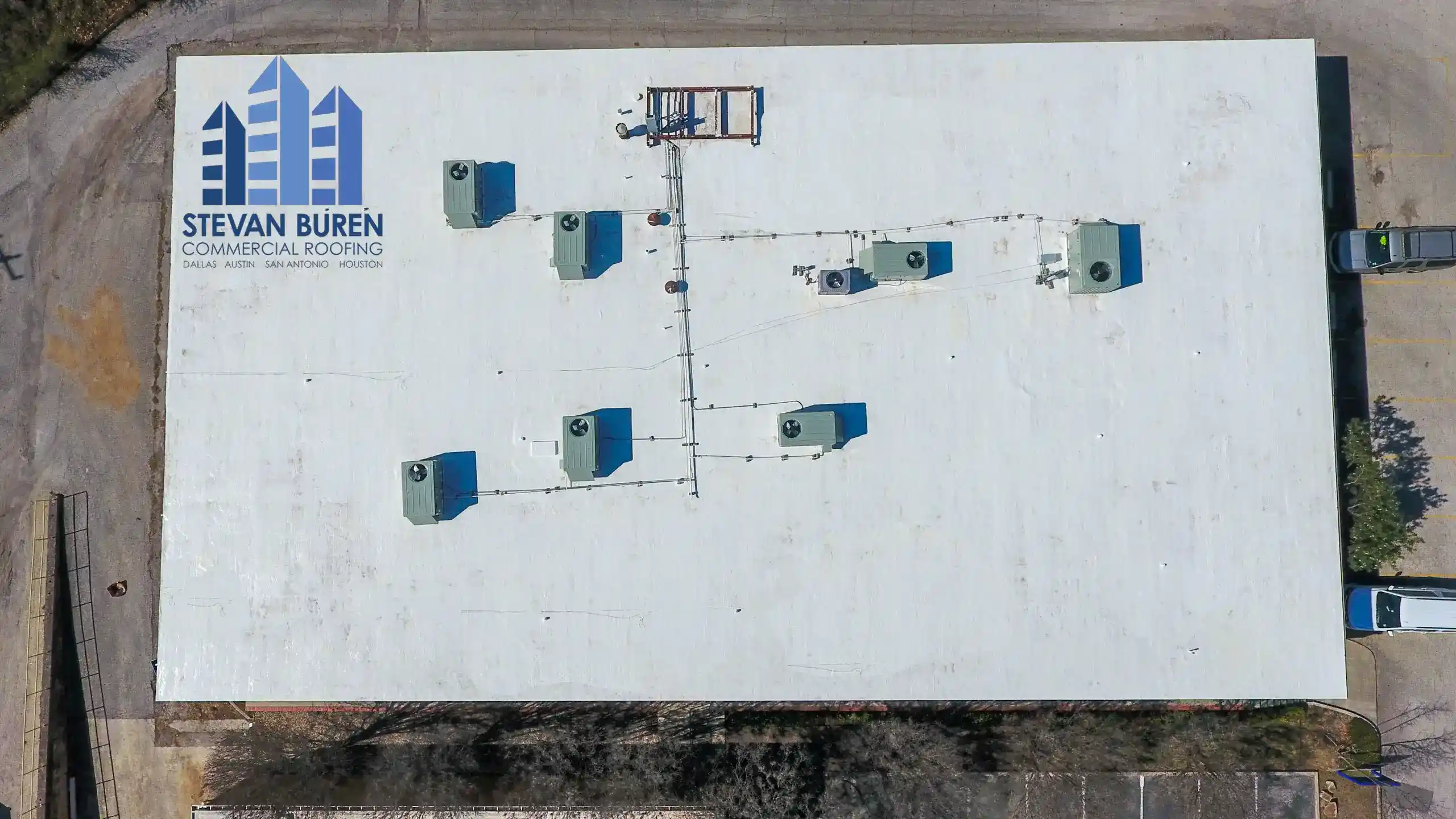 Top down aerial view of a retail building with a white roof coating system