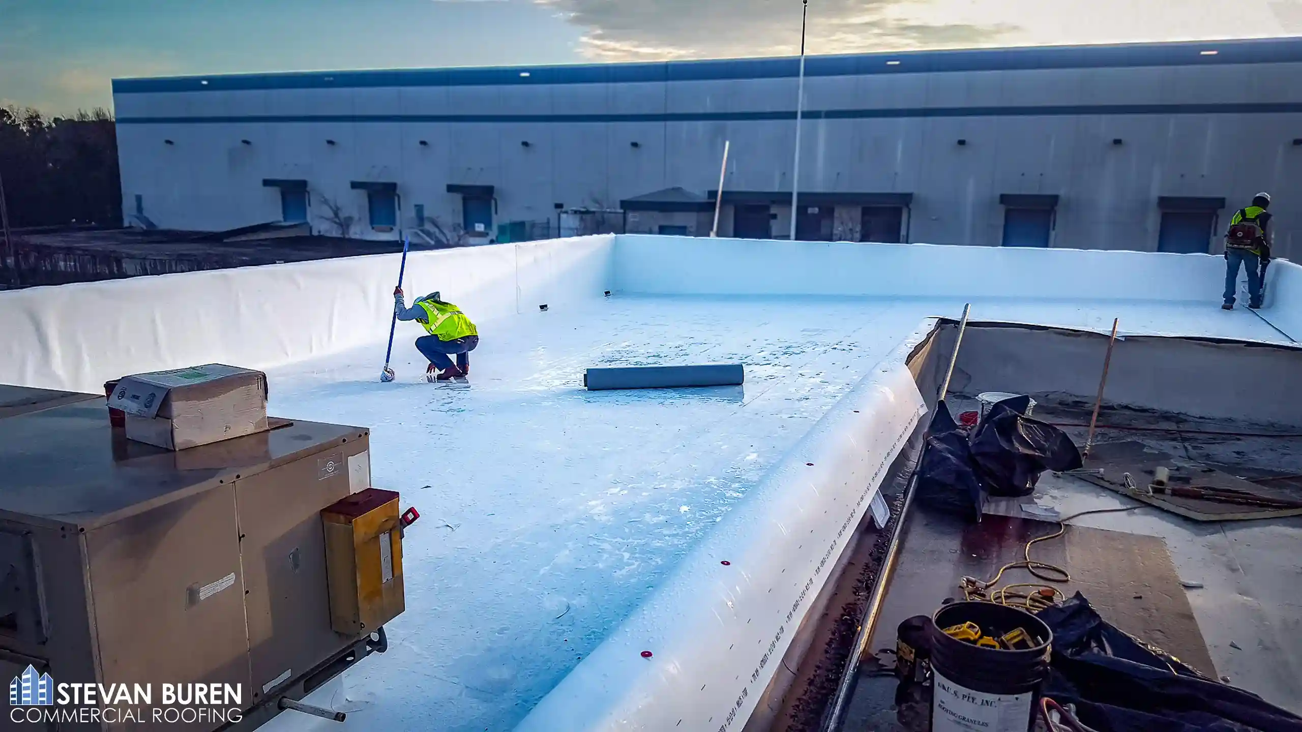 Commercial roofers installing a white TPO roofing system