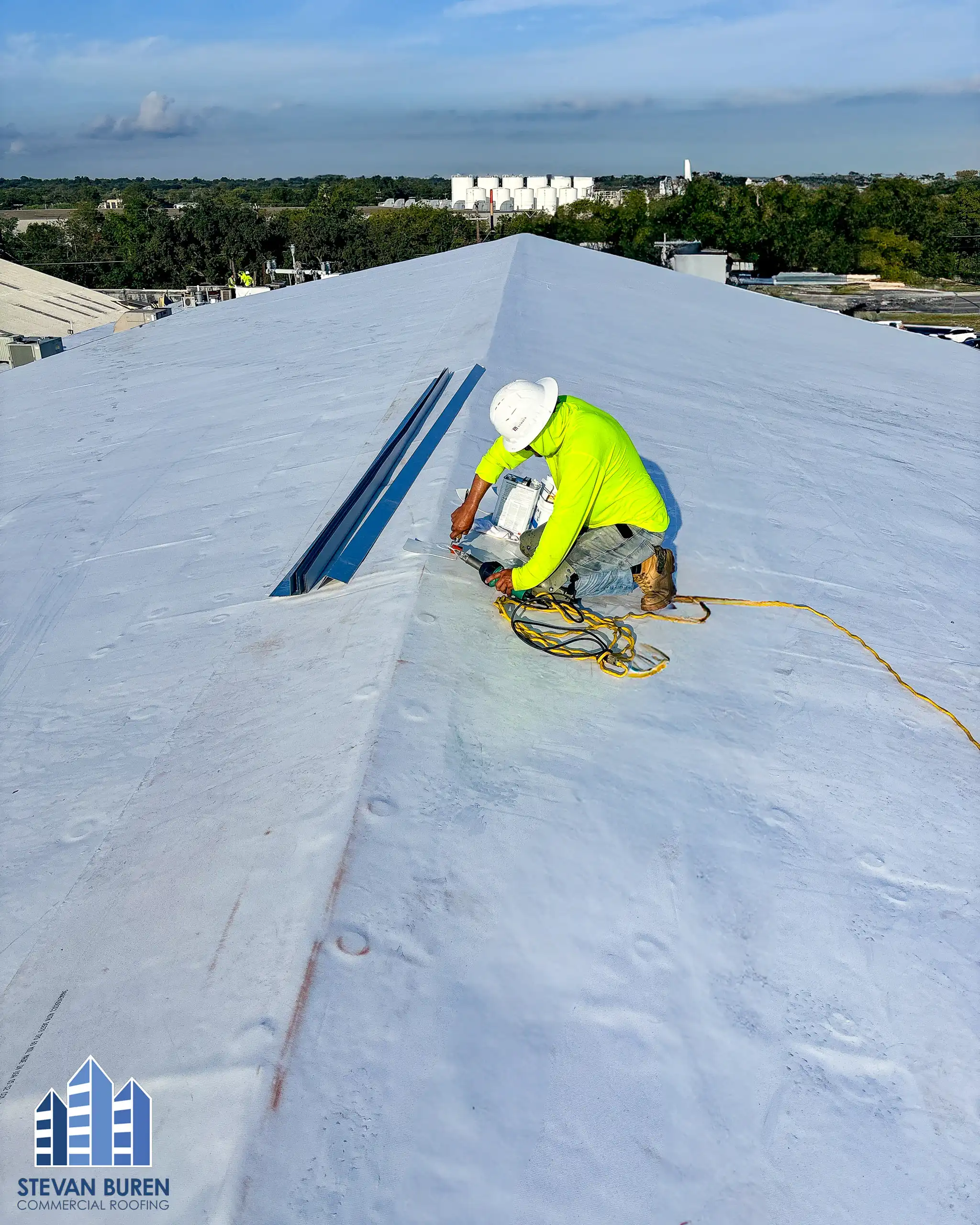 Roofer finishing work on a white TPO roof membrane